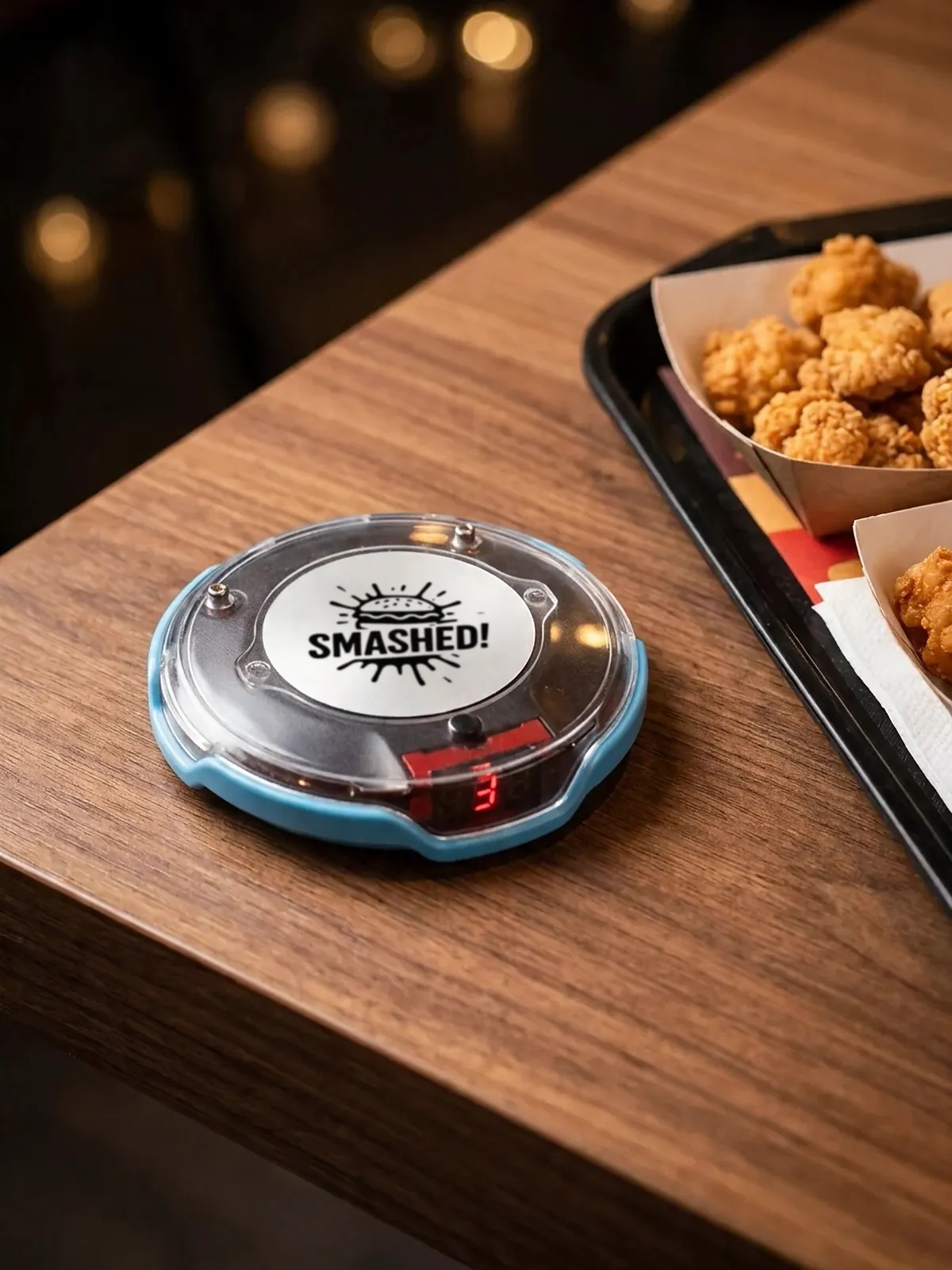 Pager mit Smashed-Logo und Nummer 3 auf dem Tisch neben dem Tablett